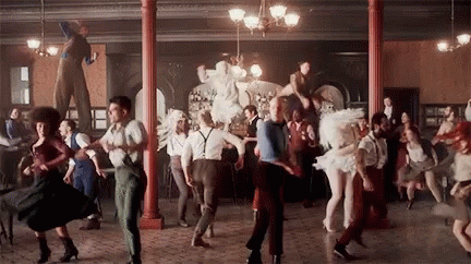 A Large Group Of People Are Dancing In A Room In A Circus . GIF