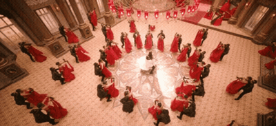 A Large Group Of People Are Dancing In A Room With A Chandelier GIF