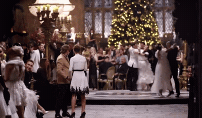 A Large Group Of People Are Dancing In A Room With A Christmas Tree In The Background GIF