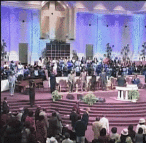 A Large Group Of People Are Gathered In A Church With Purple Lights GIF