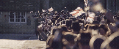 A Large Group Of People Are Standing In Front Of A Building GIF