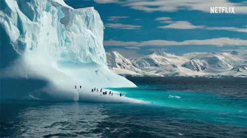 A Large Iceberg In The Middle Of The Ocean With Penguins On It And A Netflix Logo In The Background GIF
