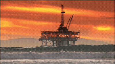 A Large Oil Rig In The Middle Of The Ocean With A Sunset In The Background GIF