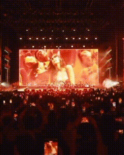 A Large Screen Shows A Group Of People On A Stage At A Concert GIF