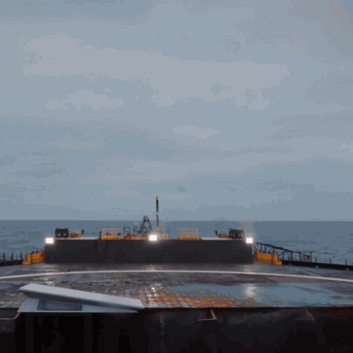 A Large Ship Is In The Middle Of The Ocean With A Few Lights On The Side GIF