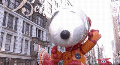 A Large Snoopy Balloon Is In Front Of A Building That Says Nbc On It GIF