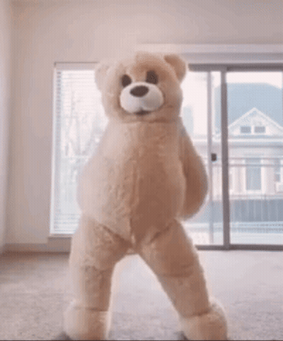 A Large Teddy Bear Is Dancing In A Room GIF