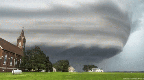 A Large Tornado Is Moving Over A Church And A Field GIF
