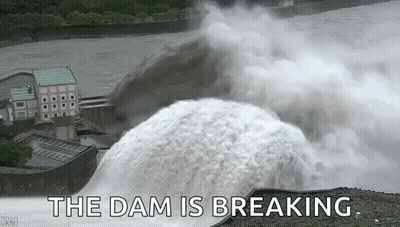 A Large Waterfall Is Coming Down A Dam With The Words `` The Dam Is Breaking '' Written Below It . GIF