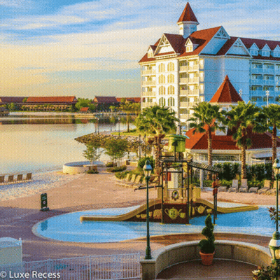 A Large White Building With A Red Roof Is Surrounded By Palm Trees And A Large Pool GIF