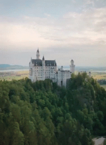 A Large White Castle Sits On Top Of A Hill GIF