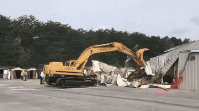 A Large Yellow Excavator Is Demolishing A Building That Says Barco On It GIF