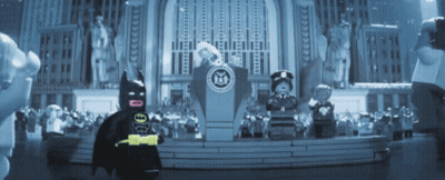 a lego batman stands in front of a podium in front of a statue of liberty