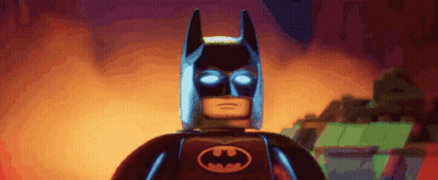 A Lego Batman With Glowing Eyes And A Bat Logo On His Chest GIF