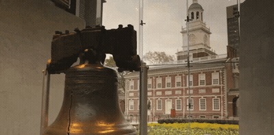 A Liberty Bell Stands In Front Of A Building GIF