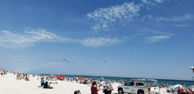 A Lifeguard Truck Is Parked On The Beach Near A Crowd Of People GIF