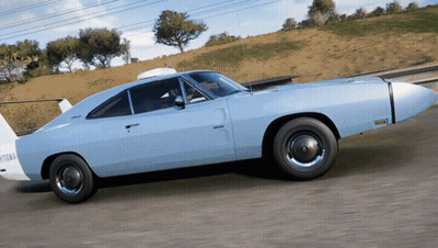 A Light Blue Muscle Car Is Driving Down A Road GIF
