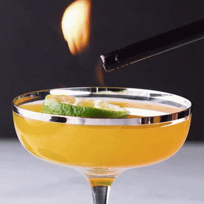 A Lighter Is Being Used To Light A Drink In A Coupe Glass GIF