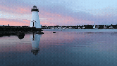 a lighthouse in the middle of a body of water at sunset