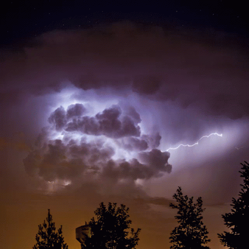 A Lightning Bolt Strikes A Cloud In A Dark Sky GIF