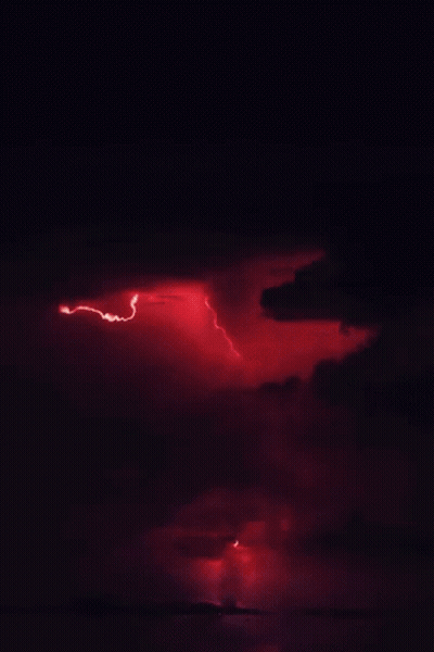 A Lightning Bolt Strikes Through A Cloudy Sky At Night GIF
