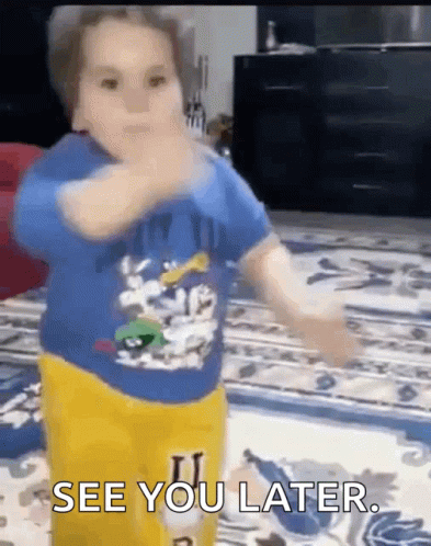 A Little Boy In A Blue Shirt And Yellow Pants Is Standing On A Rug And Says See You Later . GIF