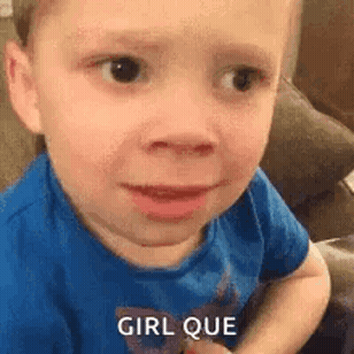 A Little Boy In A Blue Shirt Is Making A Funny Face While Sitting On A Couch . GIF