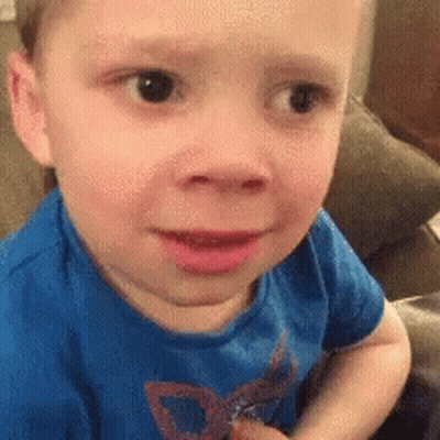 A Little Boy In A Blue Shirt Is Sitting On A Couch . GIF