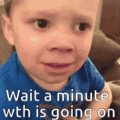 A Little Boy In A Blue Shirt Is Sitting On A Couch With The Words `` Wait A Minute Wth Is Going On '' . GIF