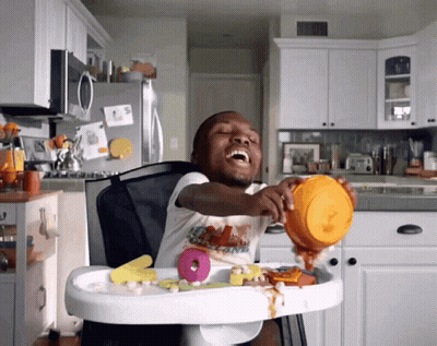A Little Boy In A High Chair With A Bowl Of Food GIF