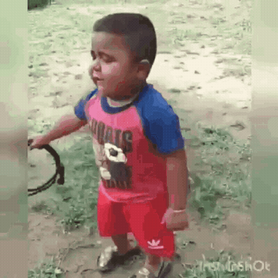 A Little Boy In A Pink Shirt And Red Shorts Is Holding A Tambourine In His Hand . GIF