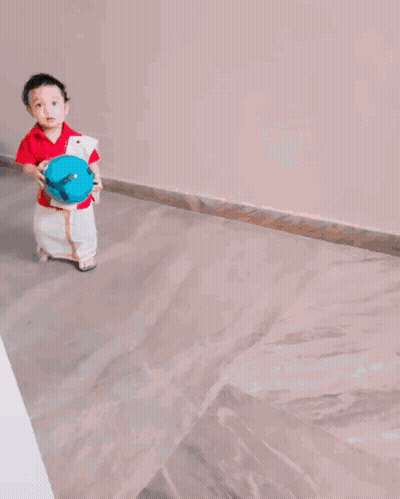 A Little Boy In A Red Shirt And White Pants Holds A Blue Ball GIF
