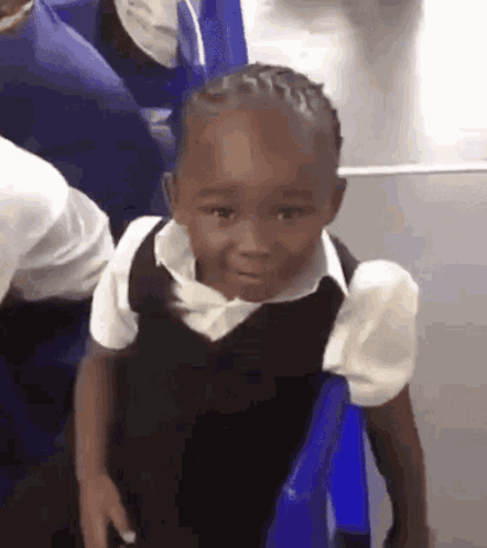 A Little Boy In A School Uniform Is Sitting On A Blue Chair And Making A Funny Face . GIF