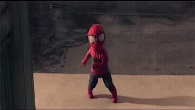 A Little Boy In A Spiderman Costume Is Walking Down The Sidewalk . GIF