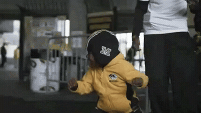 A Little Boy In A Yellow Jacket With The Letter M On It GIF