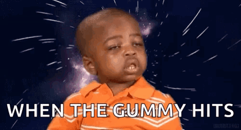 A Little Boy In An Orange Shirt Is Making A Funny Face And Saying `` When The Gummy Hits `` . GIF