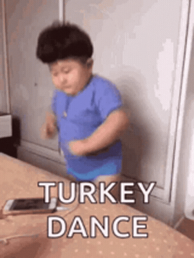 A Little Boy Is Dancing On A Bed With The Words `` Turkey Dance '' Written Above Him . GIF