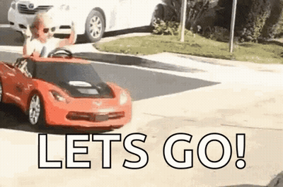 A Little Boy Is Driving A Red Toy Car On A Street . GIF