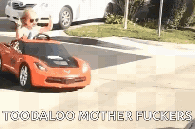 A Little Boy Is Driving A Red Toy Car On A Street . GIF