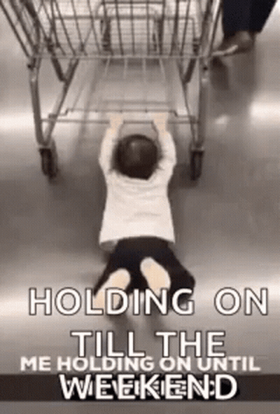A Little Boy Is Holding Onto A Shopping Cart While Crawling On The Floor . GIF