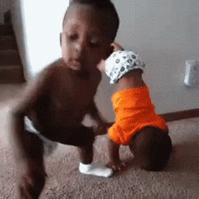 A Little Boy Is Kissing A Baby On The Cheek . GIF