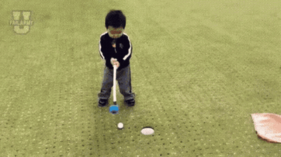 A Little Boy Is Laying On The Ground Near A Hole In The Grass . GIF