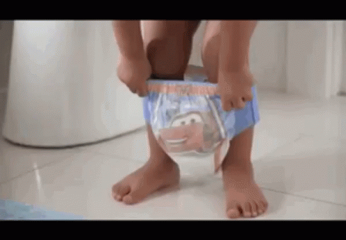 A Little Boy Is Putting On A Diaper In Front Of A Toilet . GIF