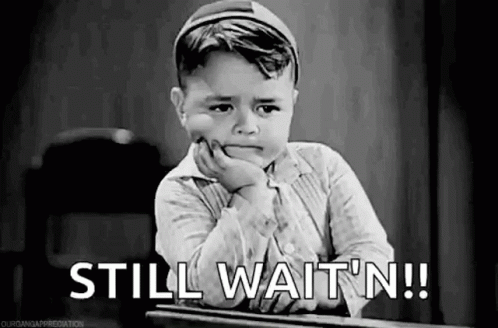 A Little Boy Is Sitting At A Desk With His Hand On His Chin And The Words `` Still Wait N '' . GIF
