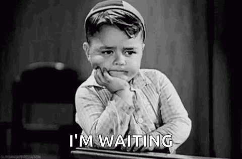 A Little Boy Is Sitting At A Desk With His Hand On His Chin And Waiting . GIF