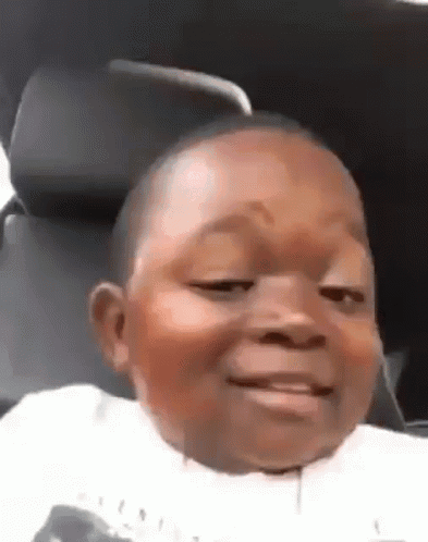 A Little Boy Is Sitting In A Car Seat And Smiling . GIF