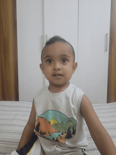 A Little Boy Is Sitting On A Bed Wearing A White Tank Top With Mountains On It GIF