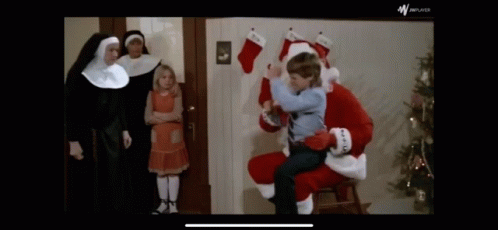 A Little Boy Is Sitting On Santa 'S Lap In Front Of Nuns GIF