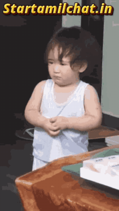 A Little Boy Is Standing In Front Of A Wooden Table With The Words Starttamilchat.in Written Above Him GIF