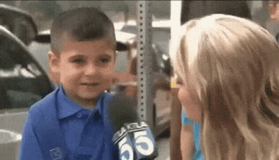 A Little Boy Is Talking To A Girl With A Microphone In His Hand . GIF